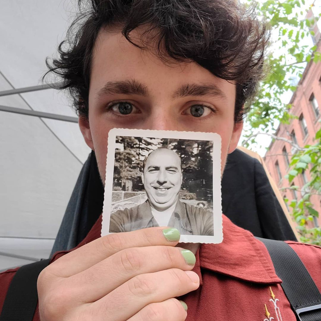 Student holds in front of their face a black-and-white photo of a smiling older person