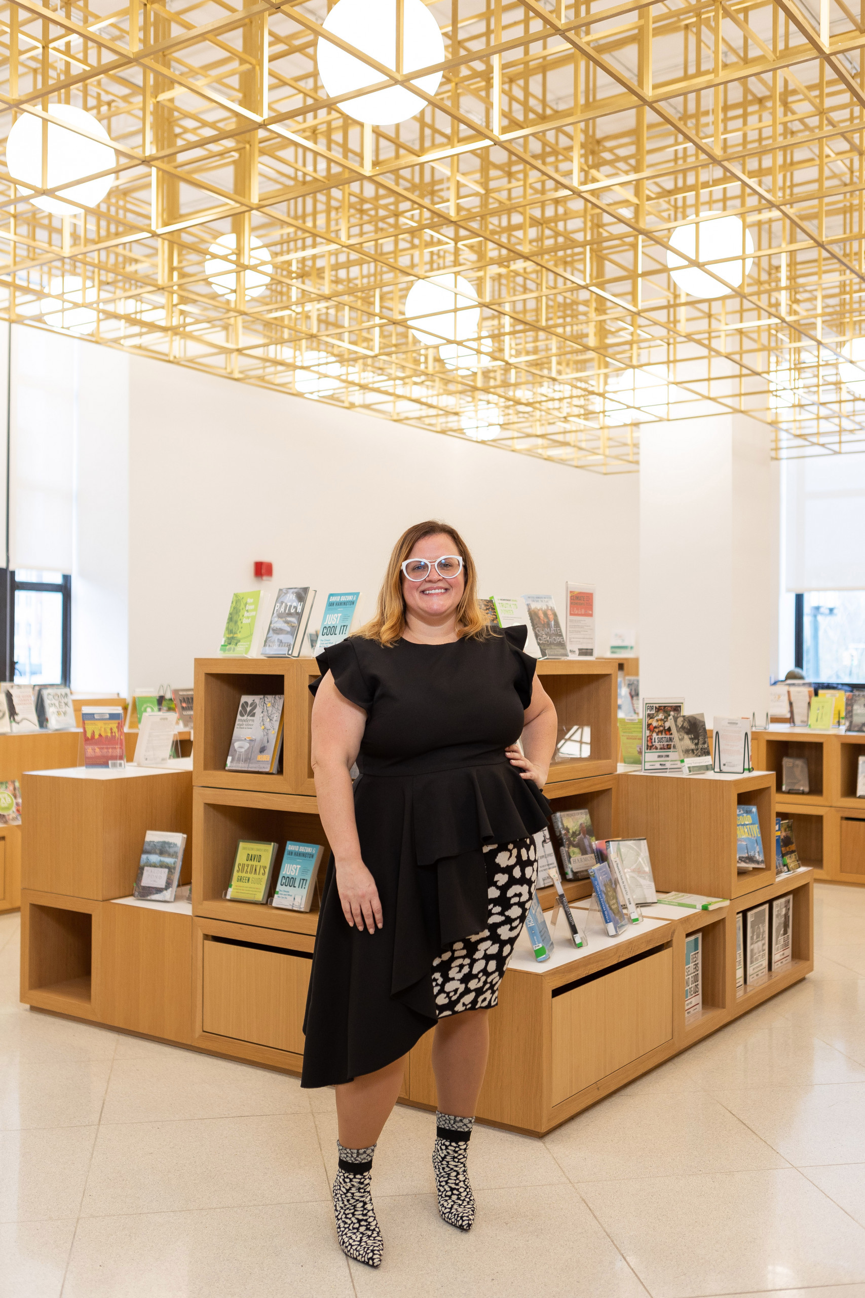 Brynna Tucker inside the Central Library in front of shelves displaying books