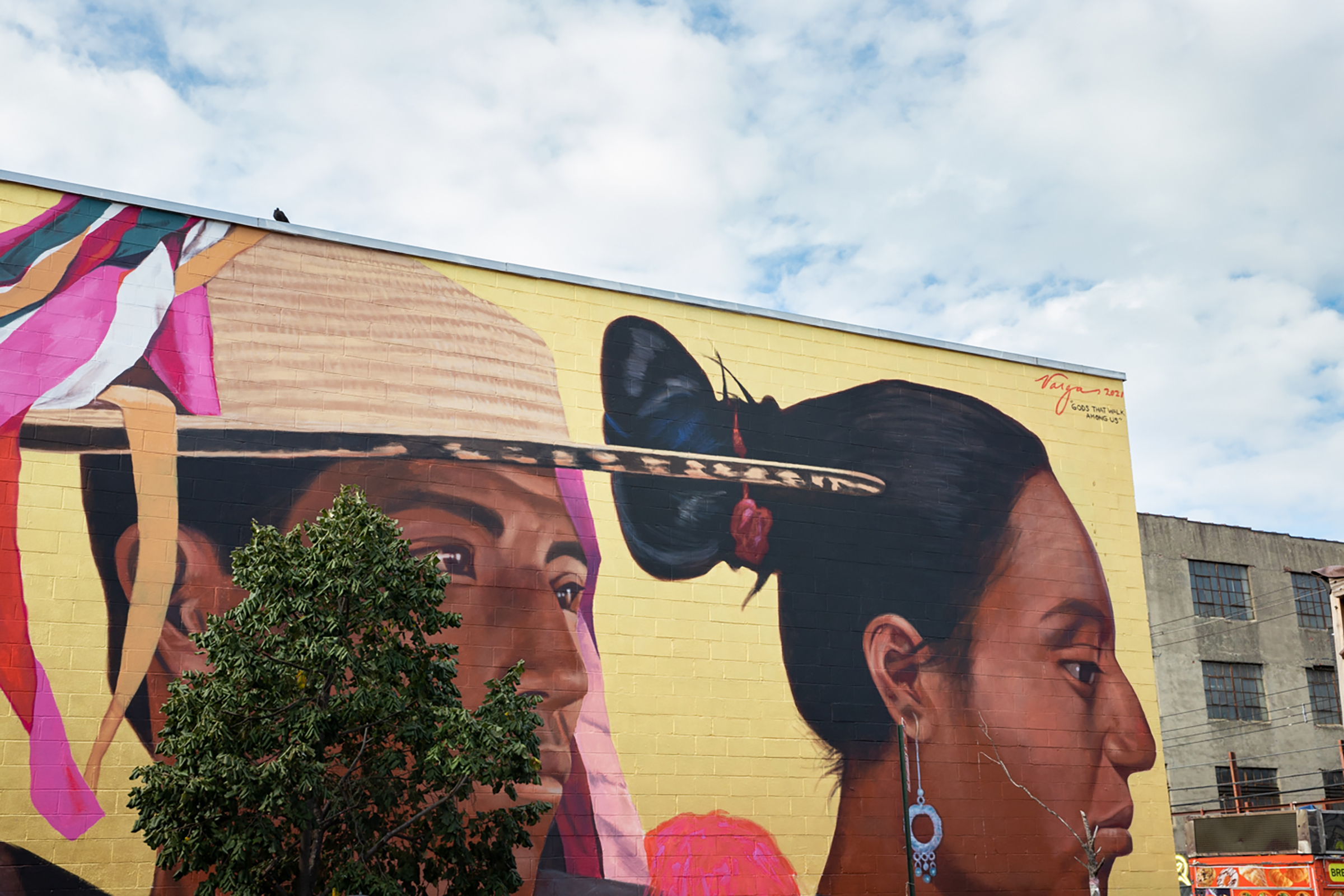 Mural with two brown-skinned people, one wearing a brimmed hat with colorful ribbons, the other with dark hair pulled in a bun and blue circular earring