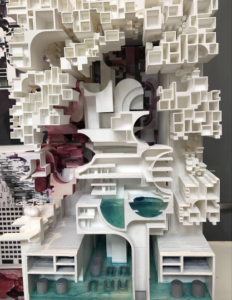 Highly detailed sectional architectural model photographed from above, showing dense modular volumes surrounding a central carved interior with layered floors, curving circulation elements, mechanical zones, and translucent blue water features at the base.
