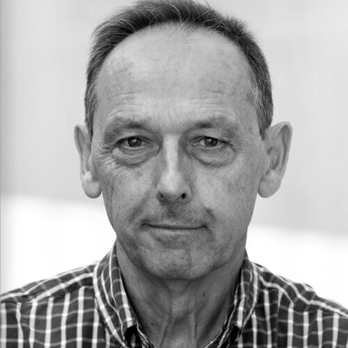 headshot of david burney, wearing a plaid button-up shirt, black and white photo