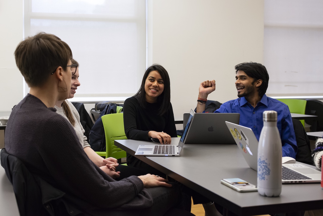 students gathering around a table, having engaged conversation