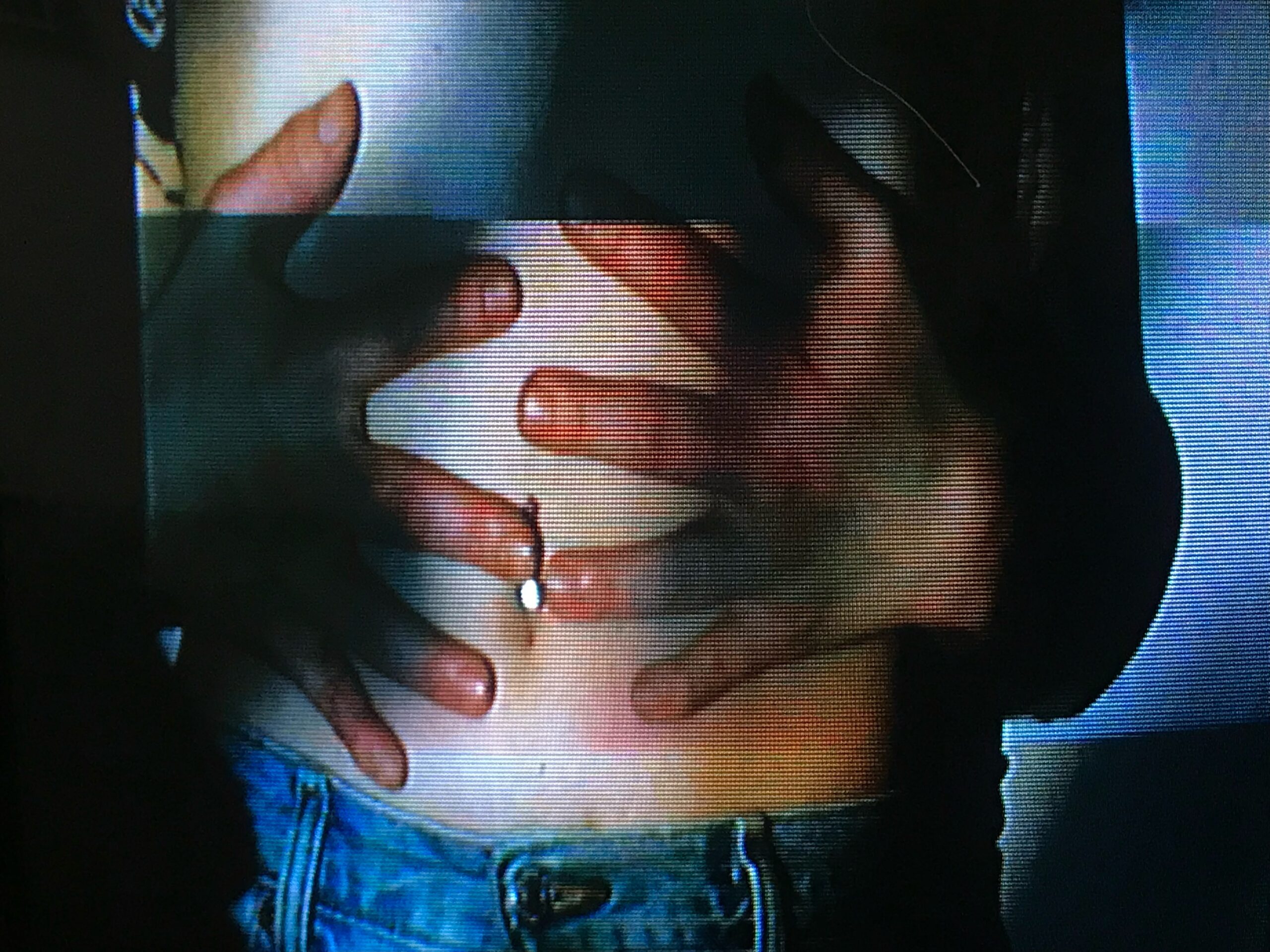A projected image onto a white wall in a dark room. A pair of hands grab a stomach with bellybutton piercing. The subject is wearing blue jeans.