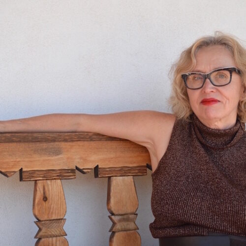 Ellen Berkovitch sitting on a wooden bench, looking at the camera.