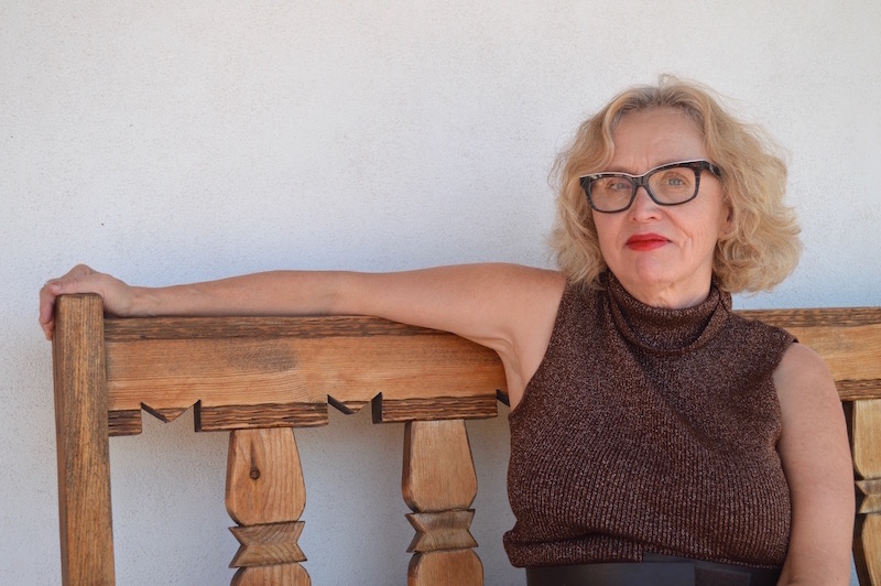 Ellen Berkovitch sitting on a wooden bench, looking at the camera.