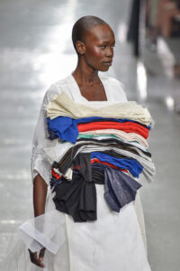 model walks the runway, wearing clothing with attachments