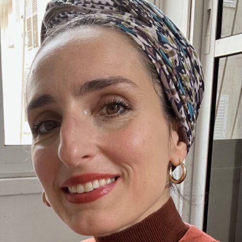 headshot of Allegra Marino Shmulevsky, wearing headwrap, smiling