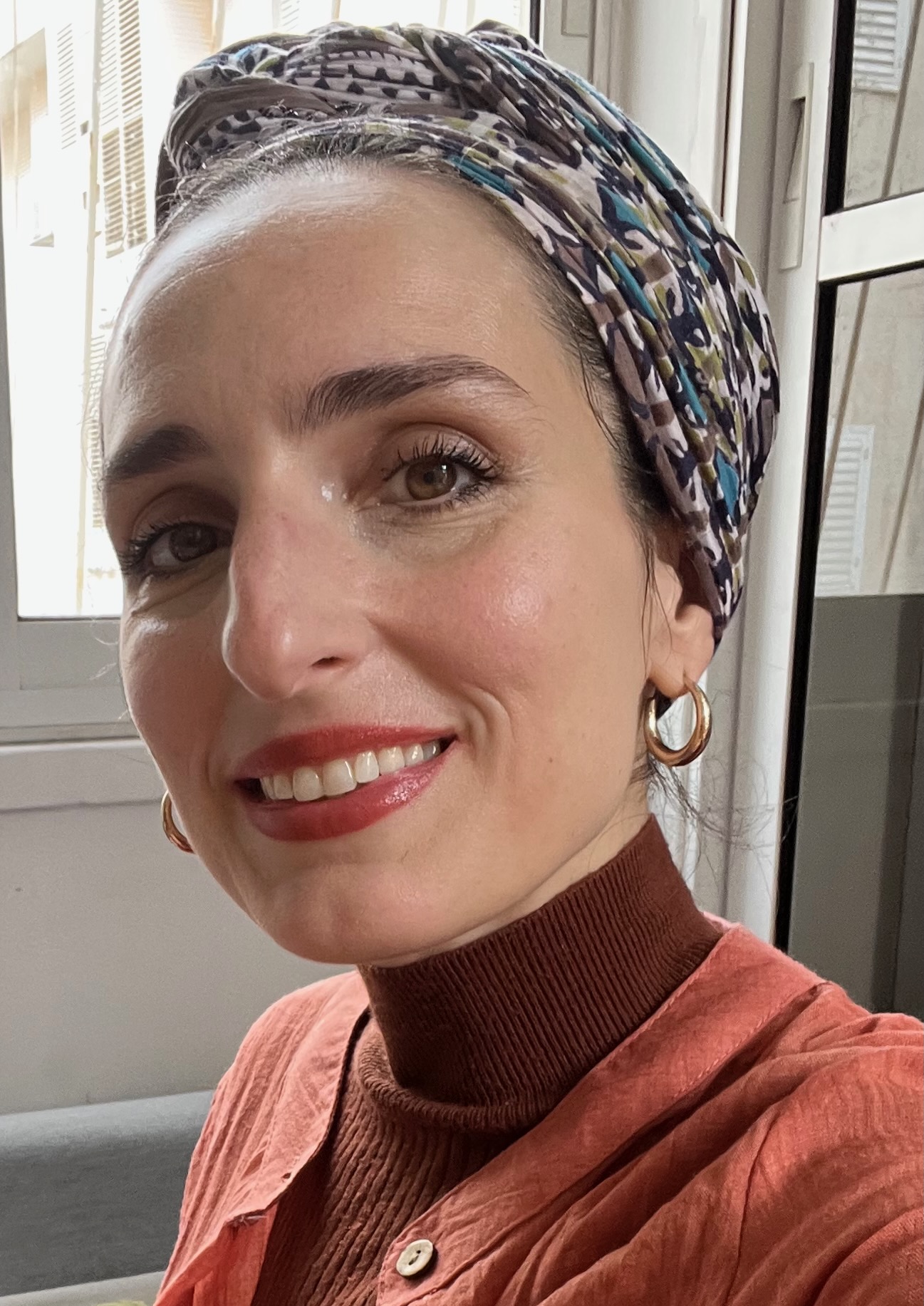 headshot of Allegra Marino Shmulevsky, wearing headwrap, smiling