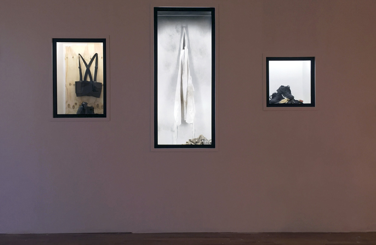 Three installations of apparel inside exhibition cases on the wall