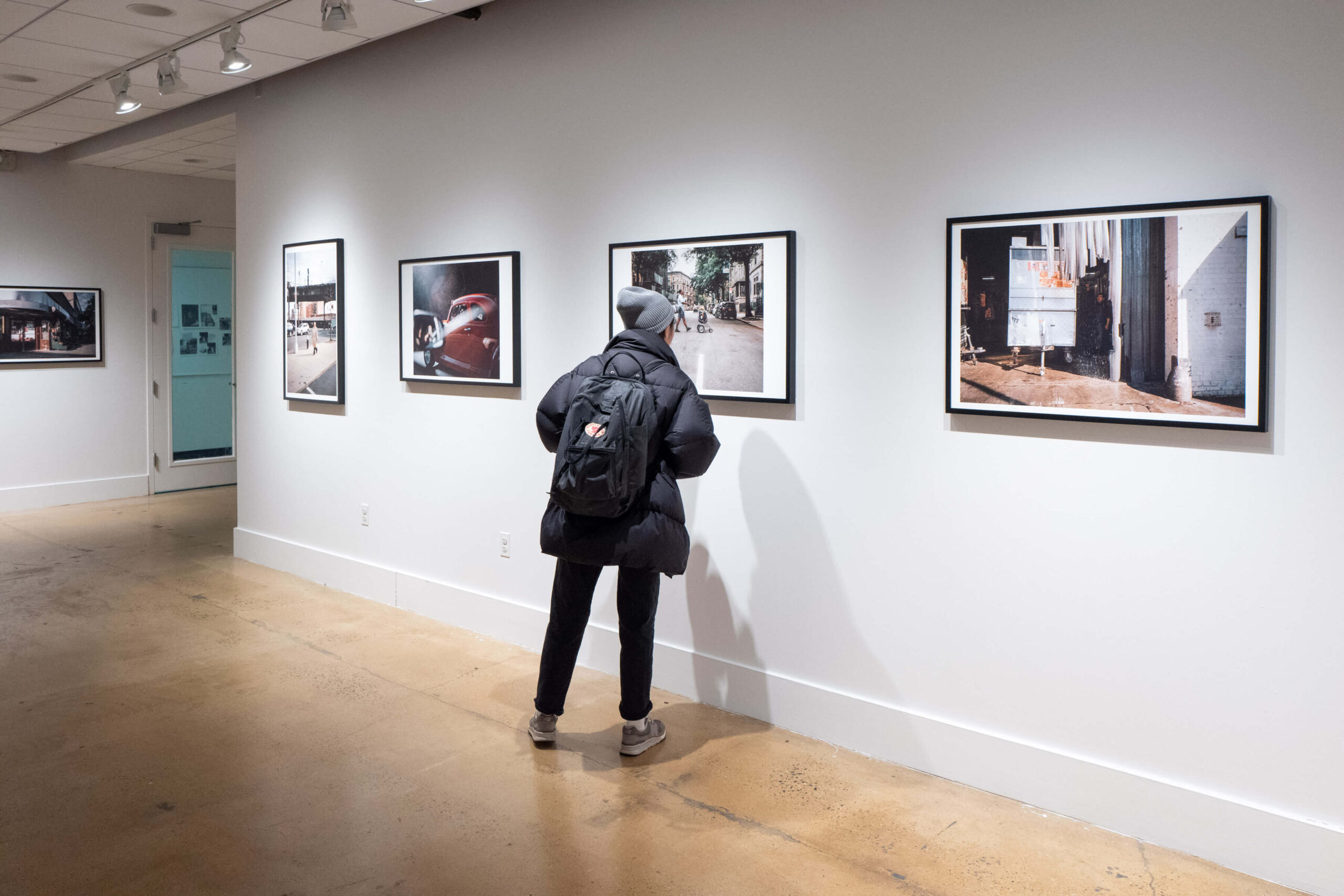 A person looks closely at a photograph in gallery with photos hung on white walls.