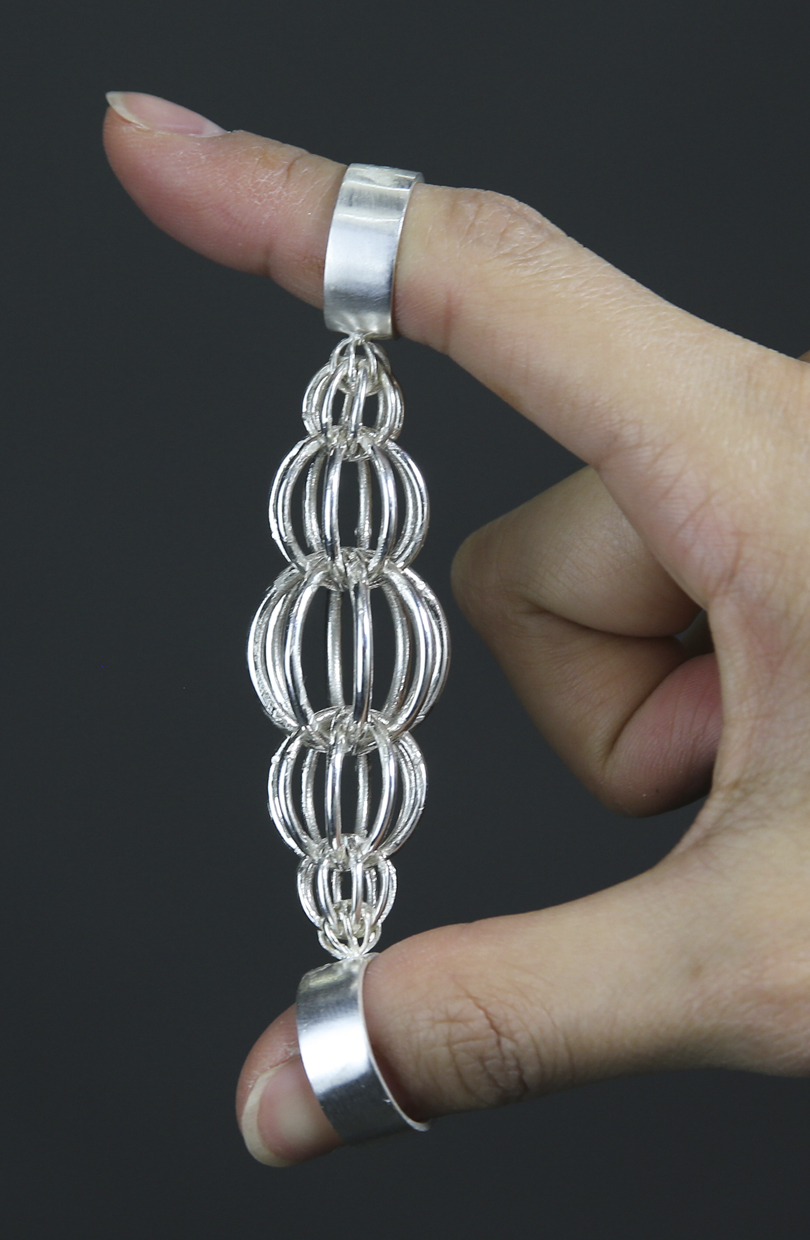A jewelry piece with multiple connecting spheres held together between the thumb and index finger