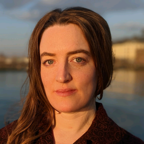 Sofia Thanhauser looks at the camera with a waterfront landscape in the background