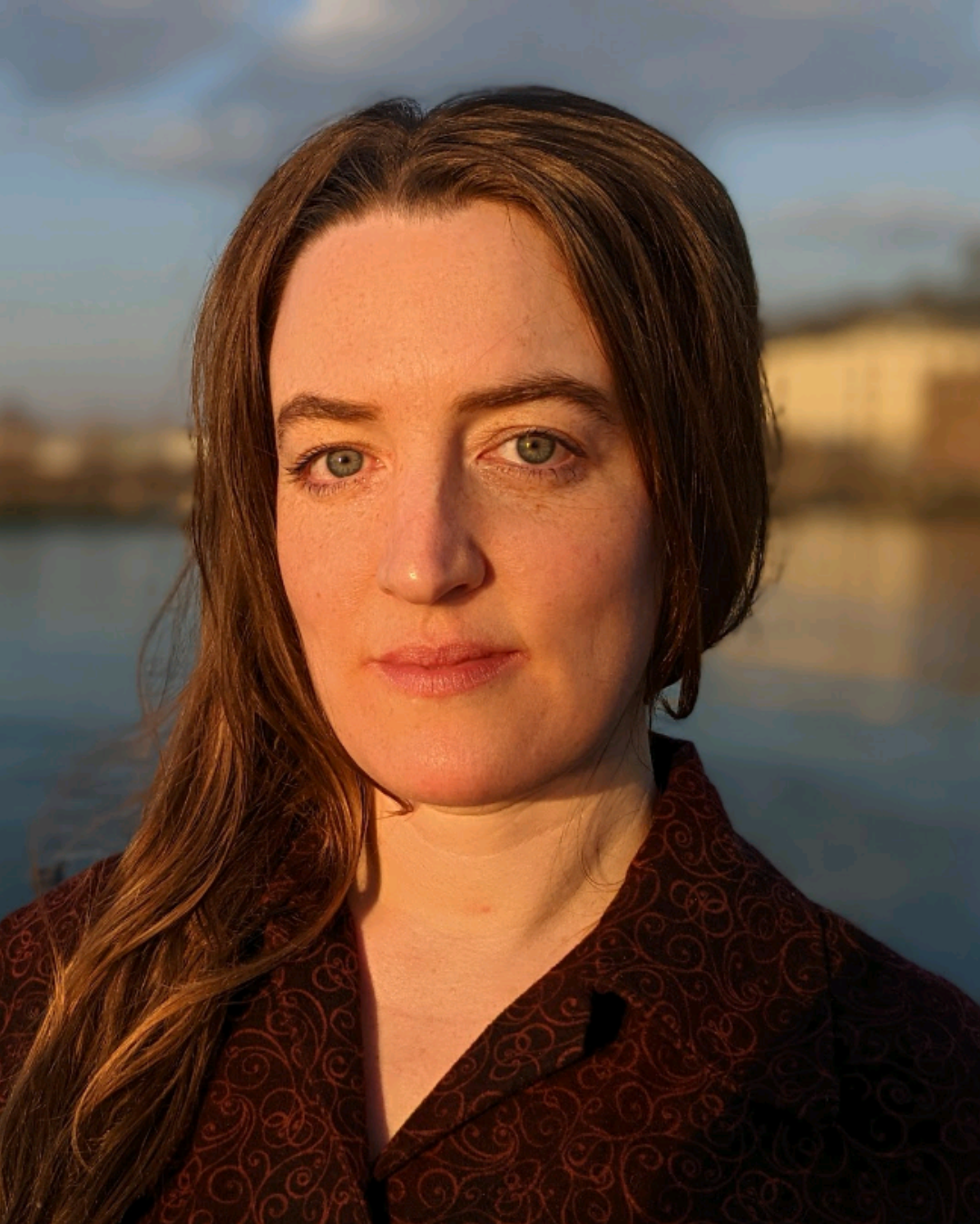 Sofia Thanhauser looks at the camera with a waterfront landscape in the background