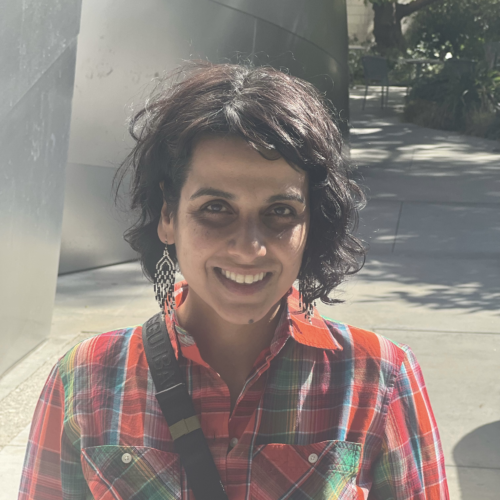 headshot of Karin Shankar, standing near concrete pillars