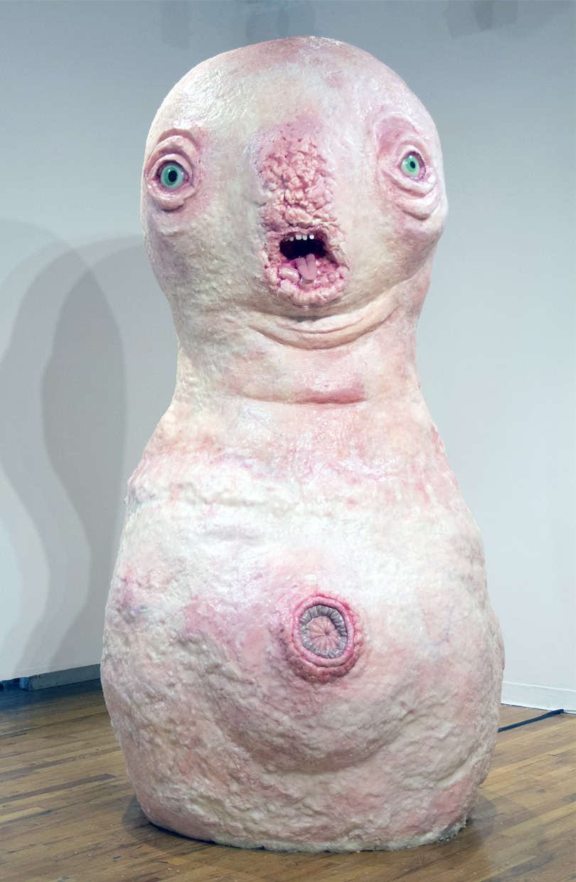 Sculpture of an anthropomorphic blob with a face and a giant belly button