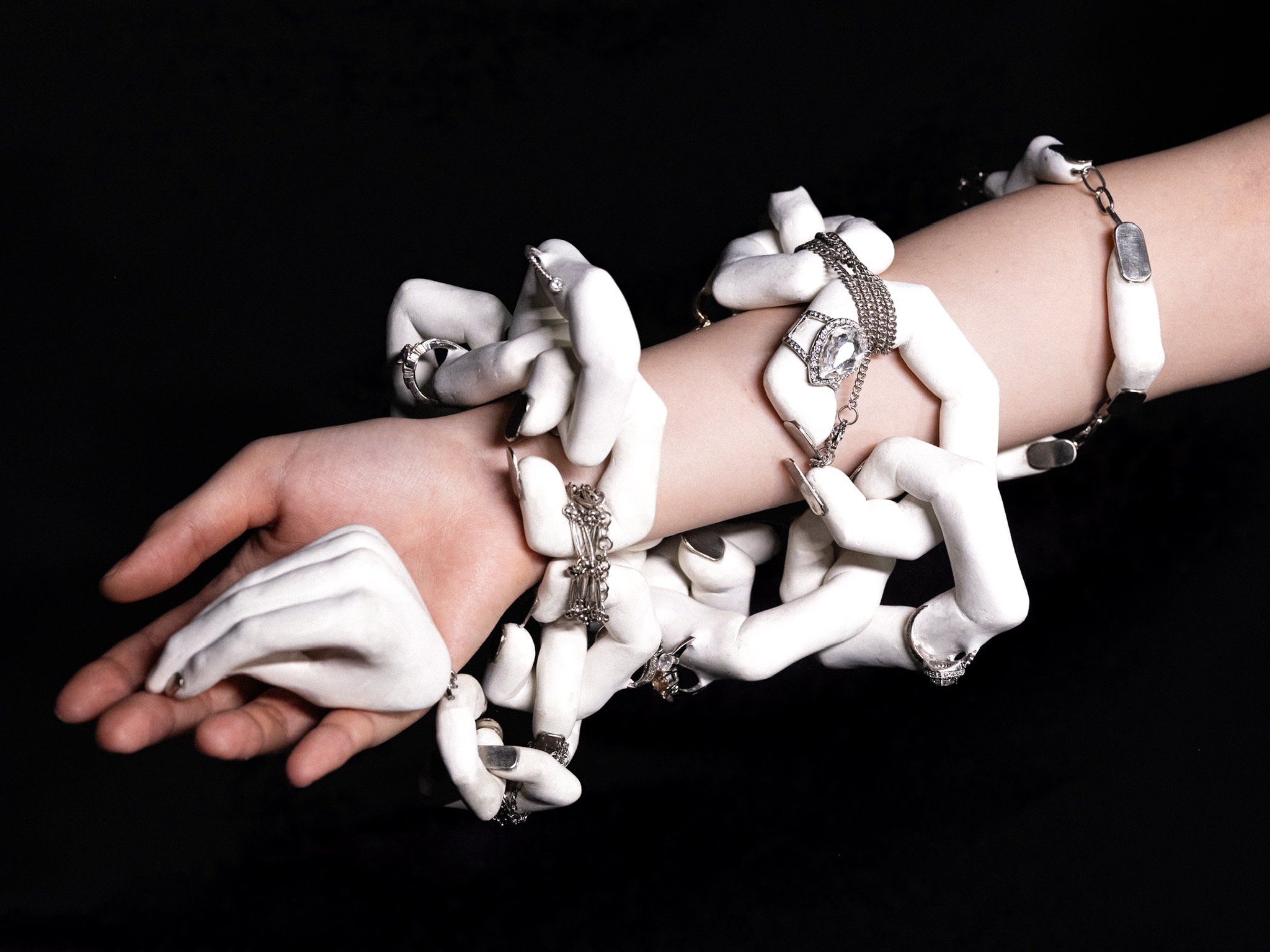 A jewelry neckpiece is wrapped around an arm. The base of the jewelry resembles a hand sitting in a person's hand.