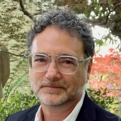 Headshot of John Beller, standing in tree-lined area