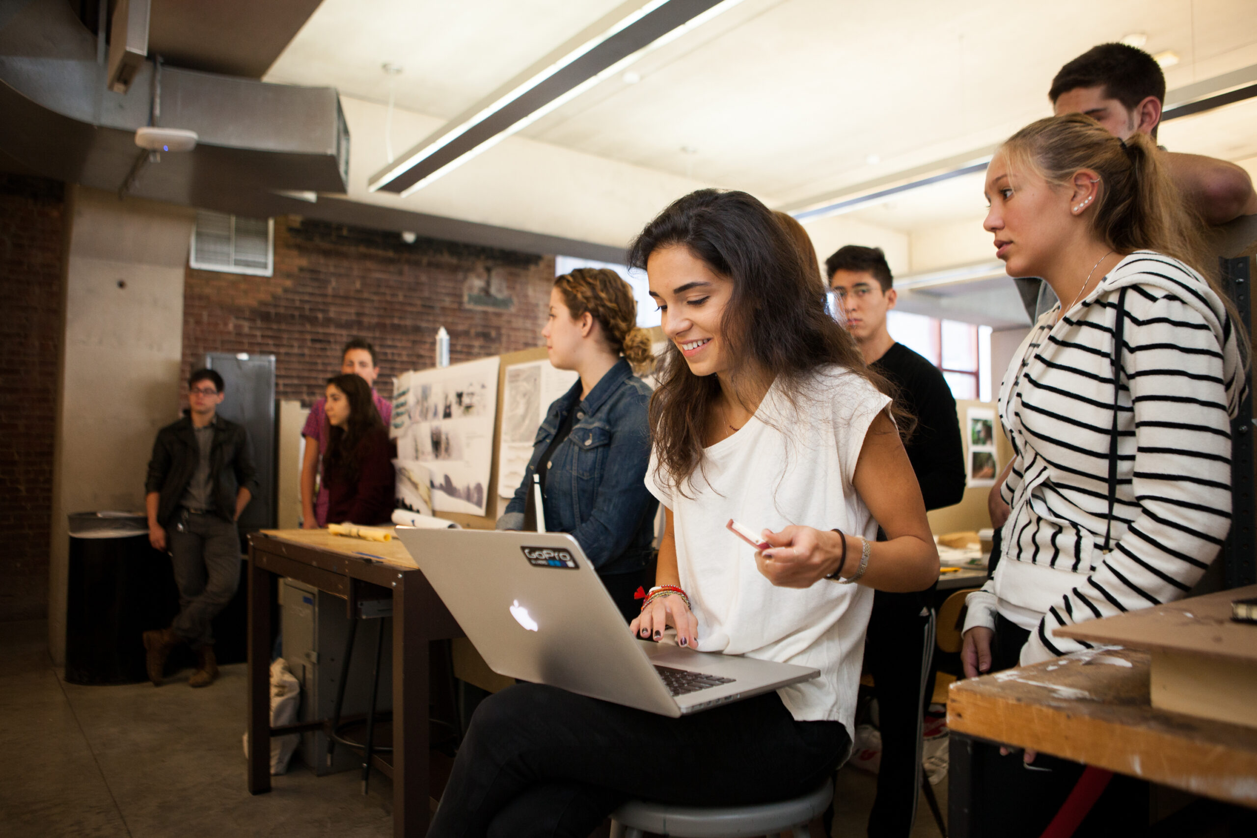 A group of students sit in a classroom attentively looking at the front of the room.
