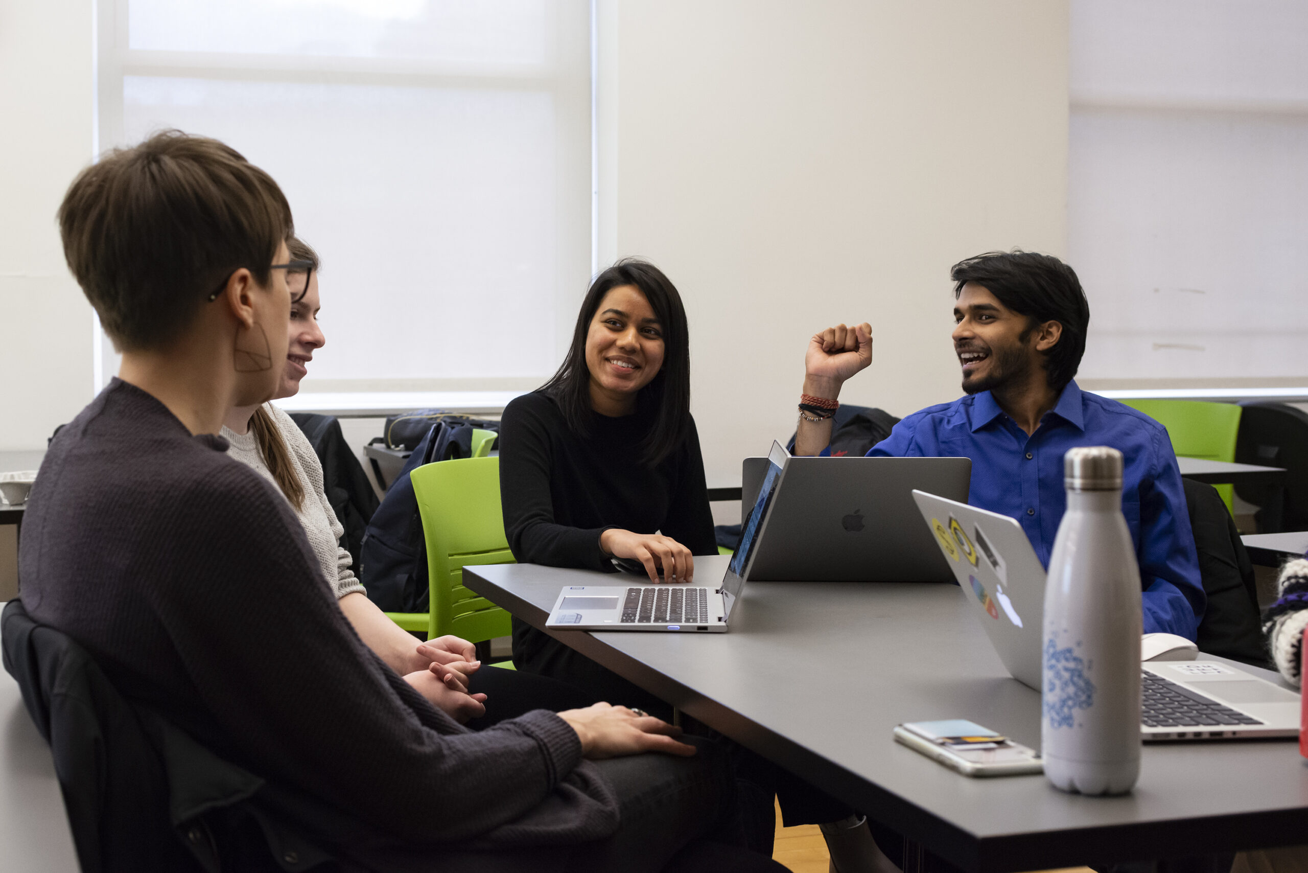 A group of staff sit around a table with their laptops and water bottles.