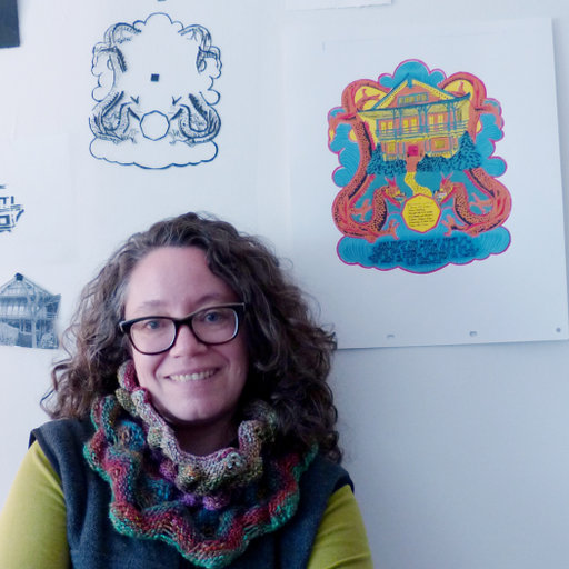 Nancy Seidler smiles directly at the camera. She is in front of a white wall with several drawings hanging from it.