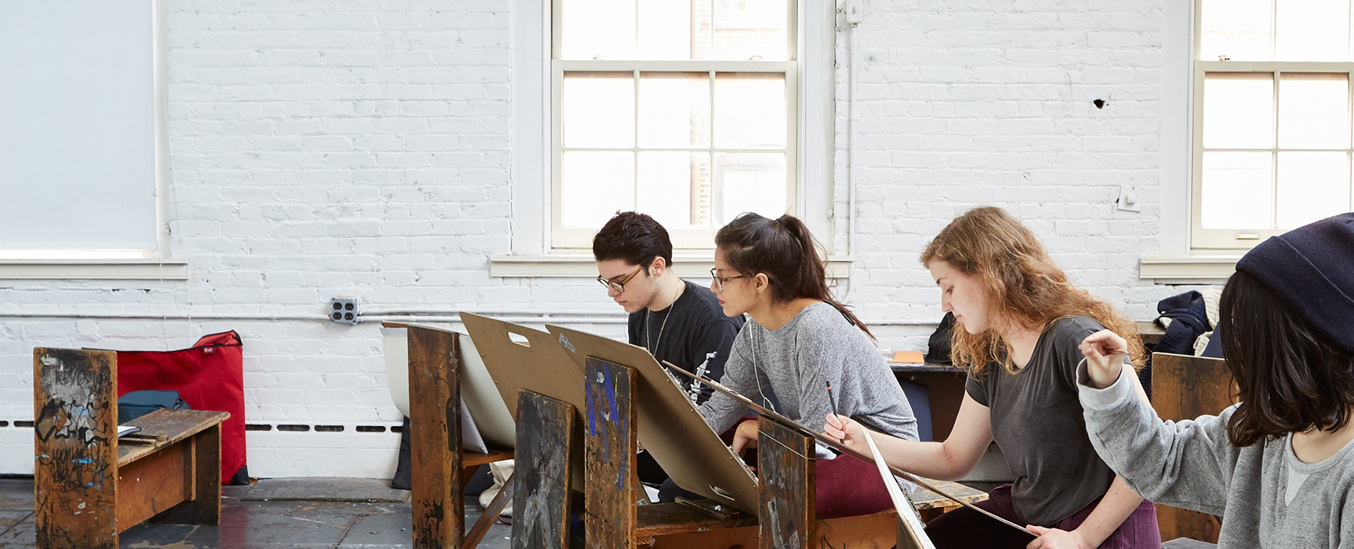 Four student sit in front of stencils as they sketch.