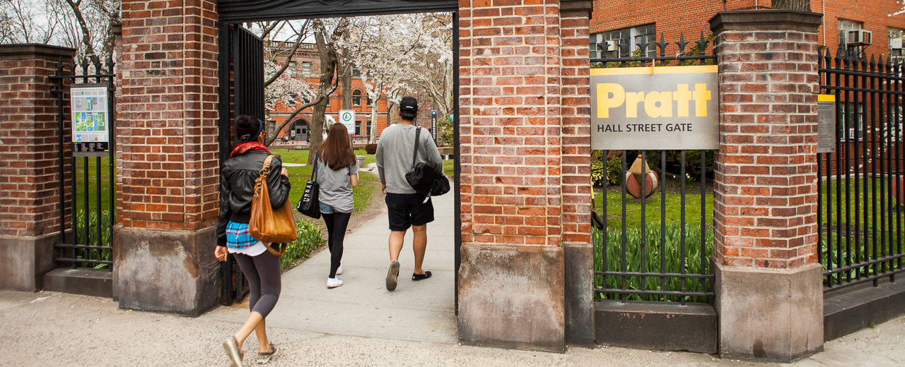 three students walk through DeKalb Gate onto Pratt campus.