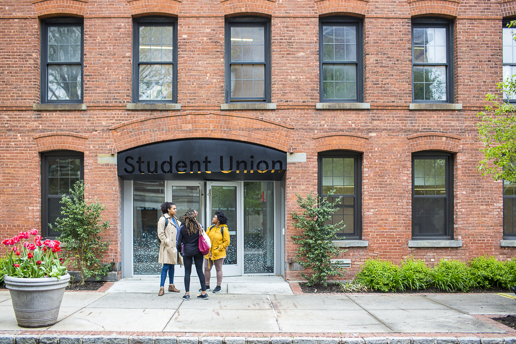 Two students are standing in front of a building labeled
