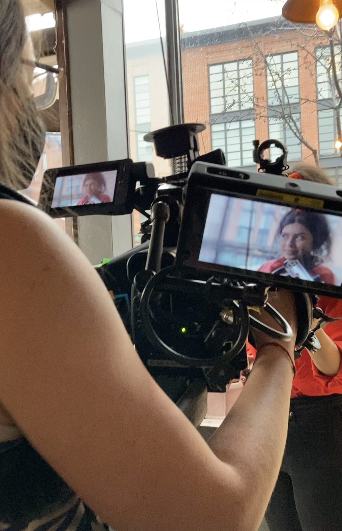 a camera's viewfinder point-of-view of a young woman in a red shirt playing the violin.