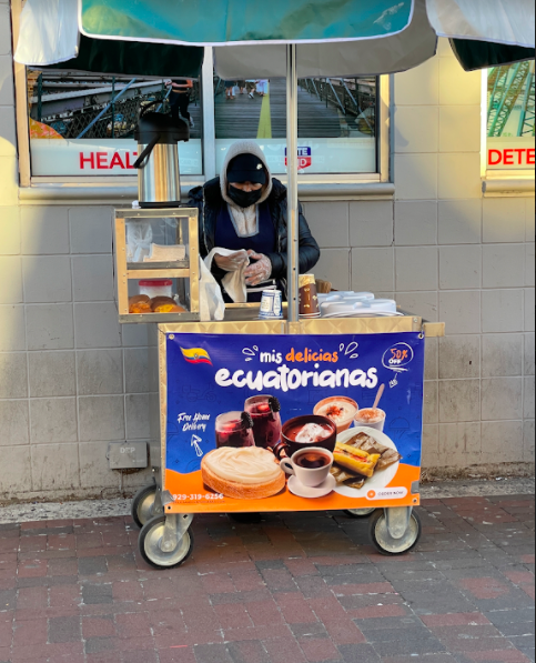 person serving coffee and pastries from a food cart on the sidewalk