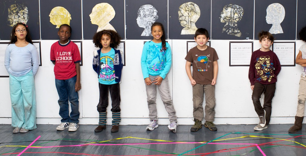 Children stand in front of artwork they created.