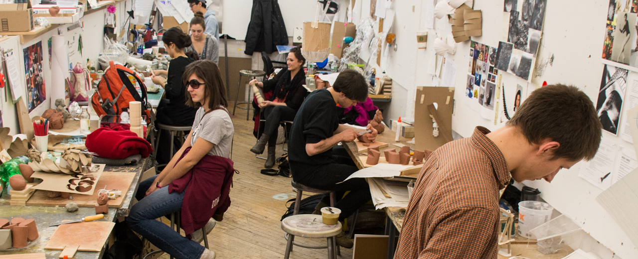 A group of students work inside an art studio with stencils in front of them.