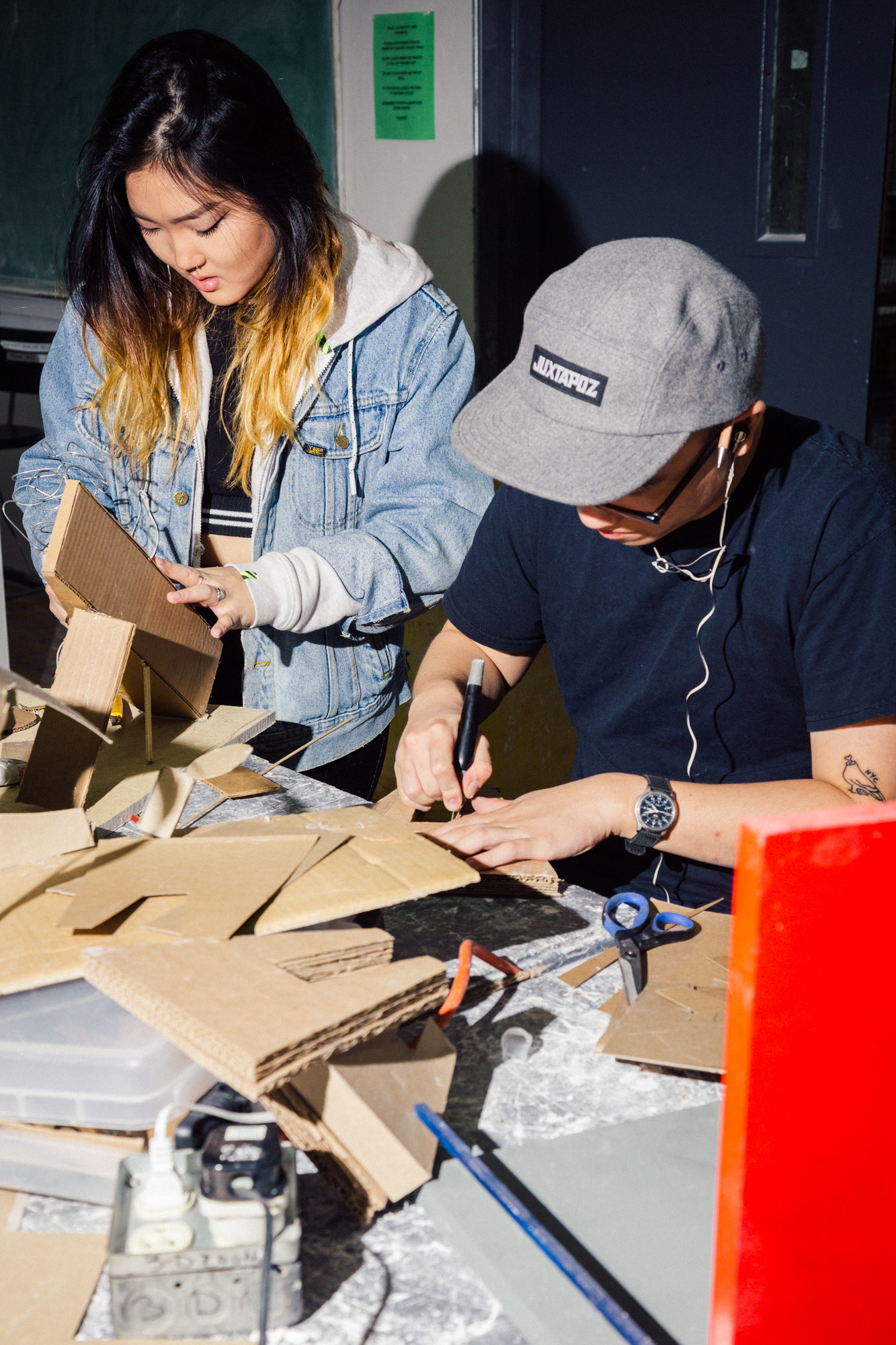 two students working in wood shop, sanding parts
