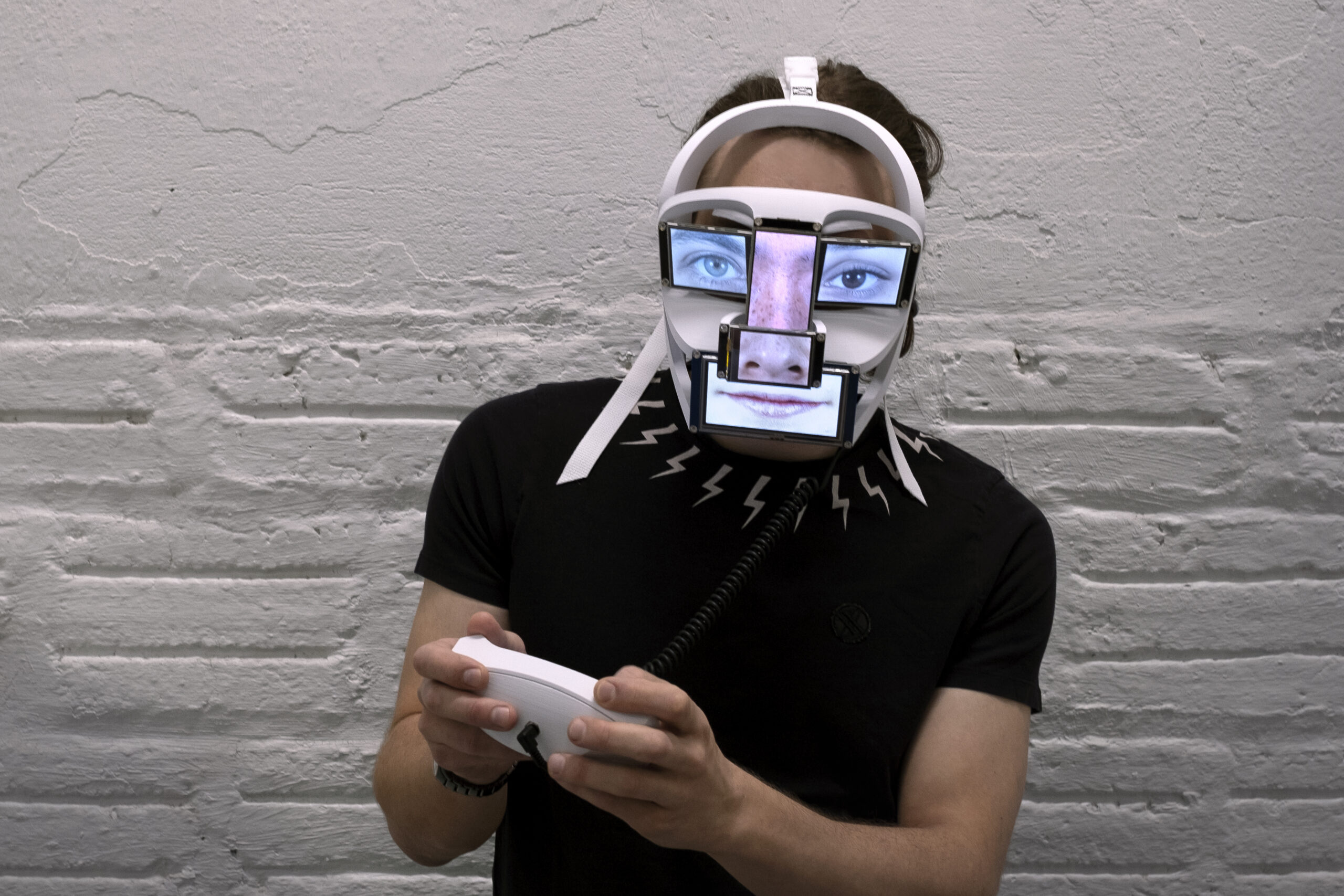 A photograph of a digital sculpture worn as a VR headset and with images on outer screens.