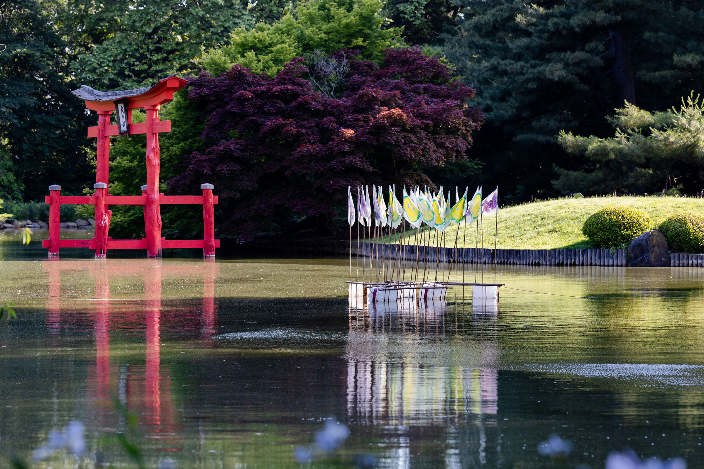 Image of a floating sculpture at the Brooklyn Botanic garden. The sculptures consists of a set of flags mounted onto a floating platform.