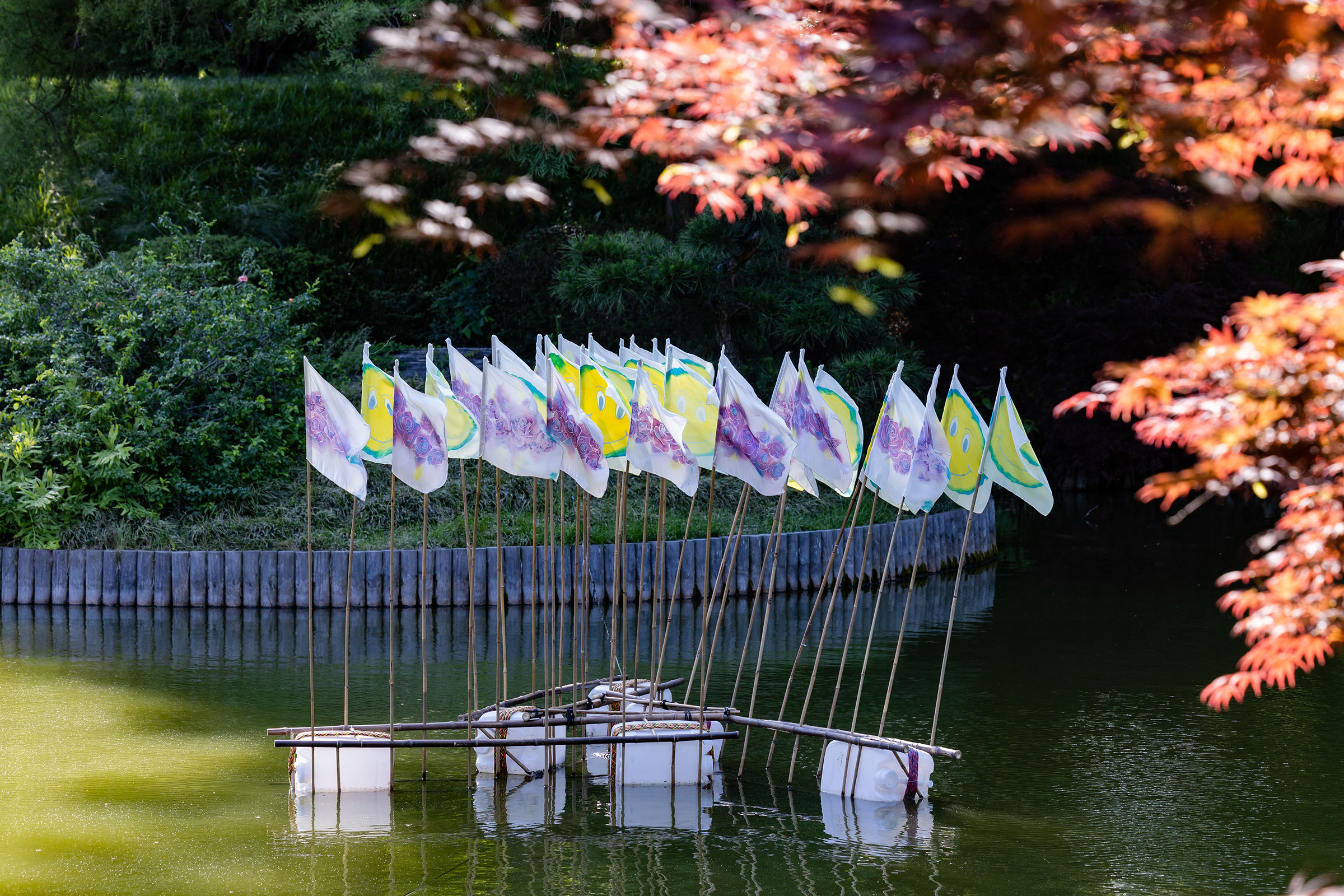 Close up image of a floating sculpture at the Brooklyn Botanic garden. The sculptures consists of a set of flags mounted onto a floating platform.