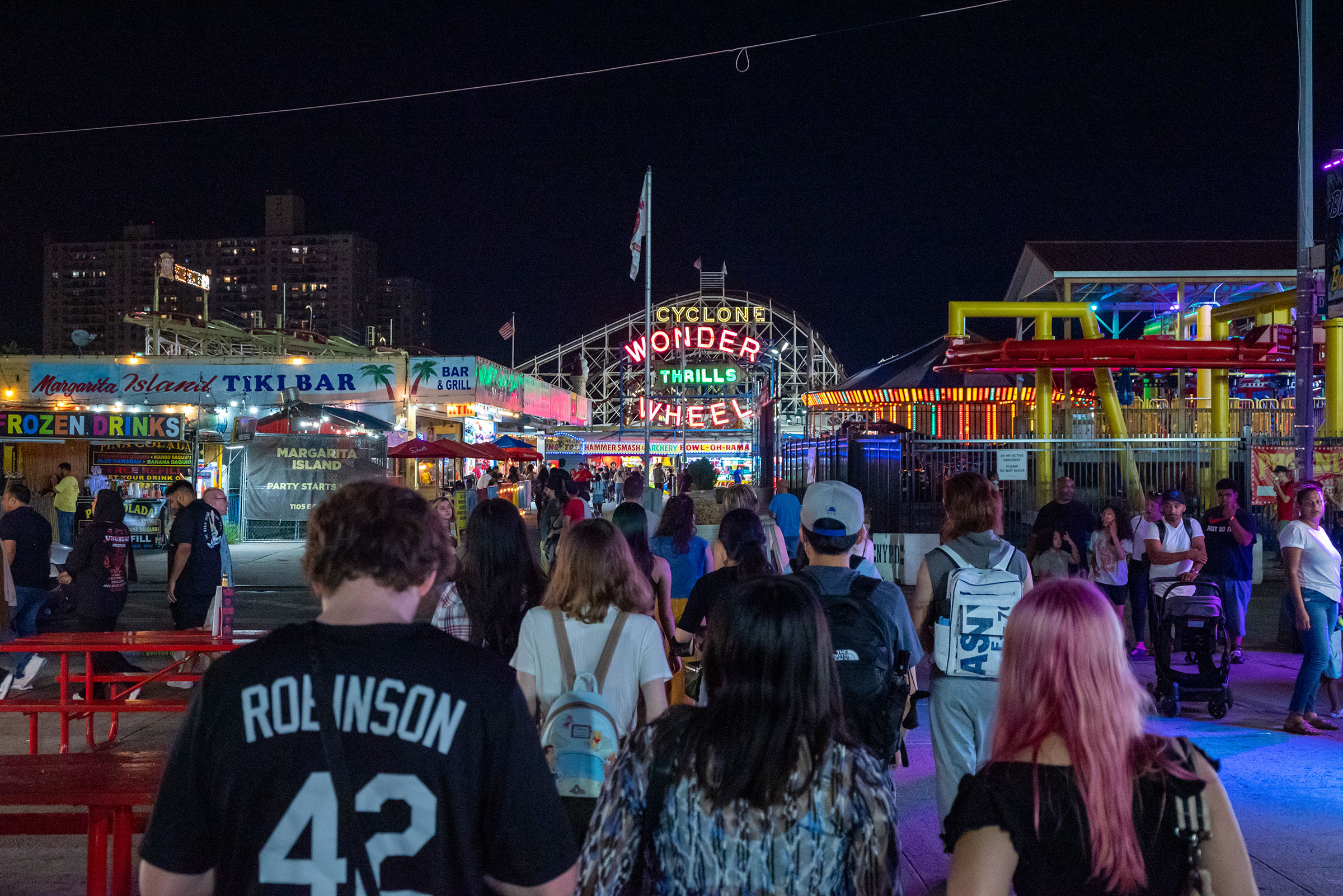a photo looking over the backs and heads of a group of college students approaching Coney Island's amusement park.