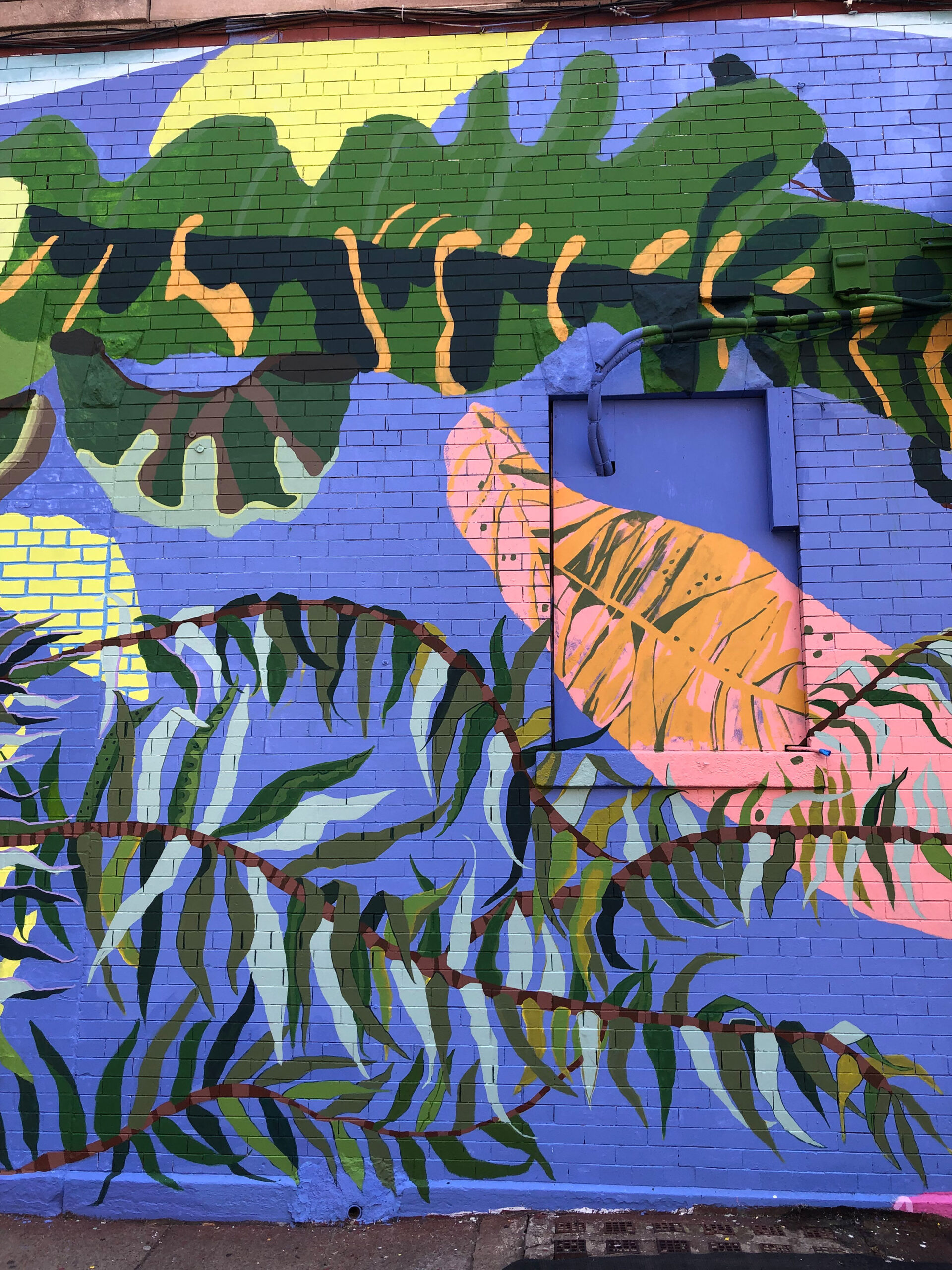 A close up of a street mural with leaves and branches of different types of trees in a range of pastel colors.