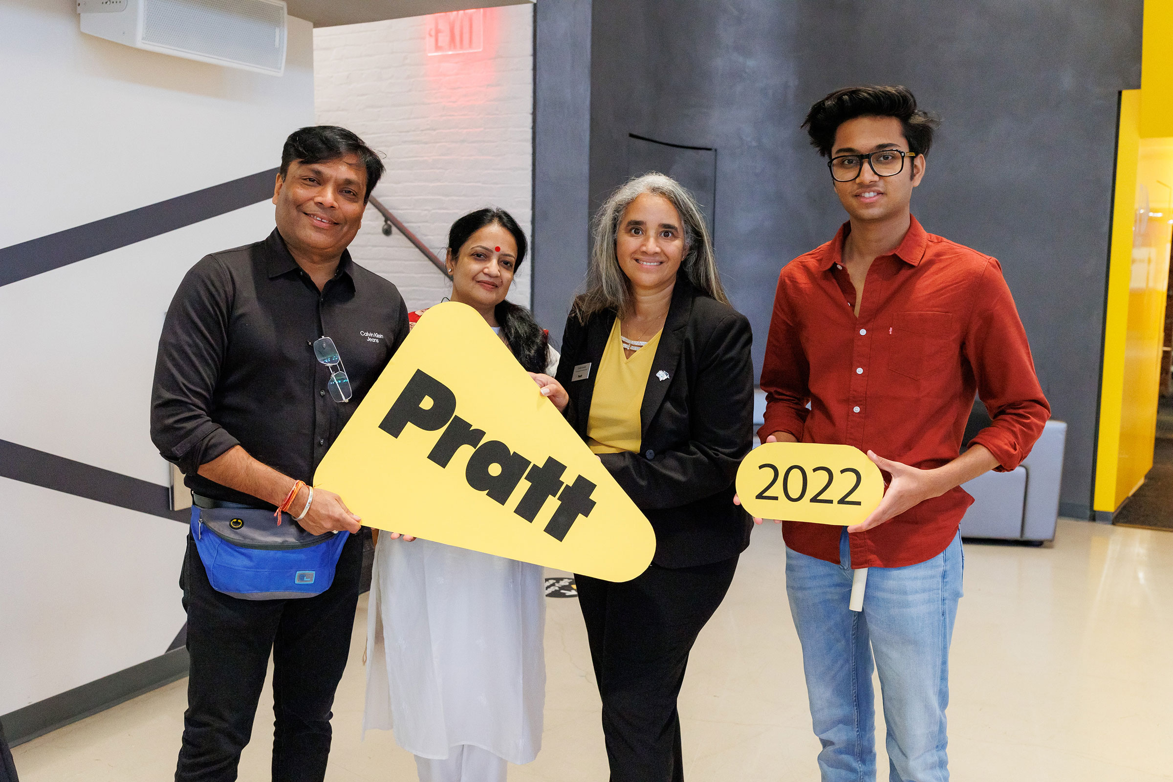 A student, their parents, and VP for Student Affairs, Delmy Lendof smile at the camera. They are holding signs that read Pratt and 2022