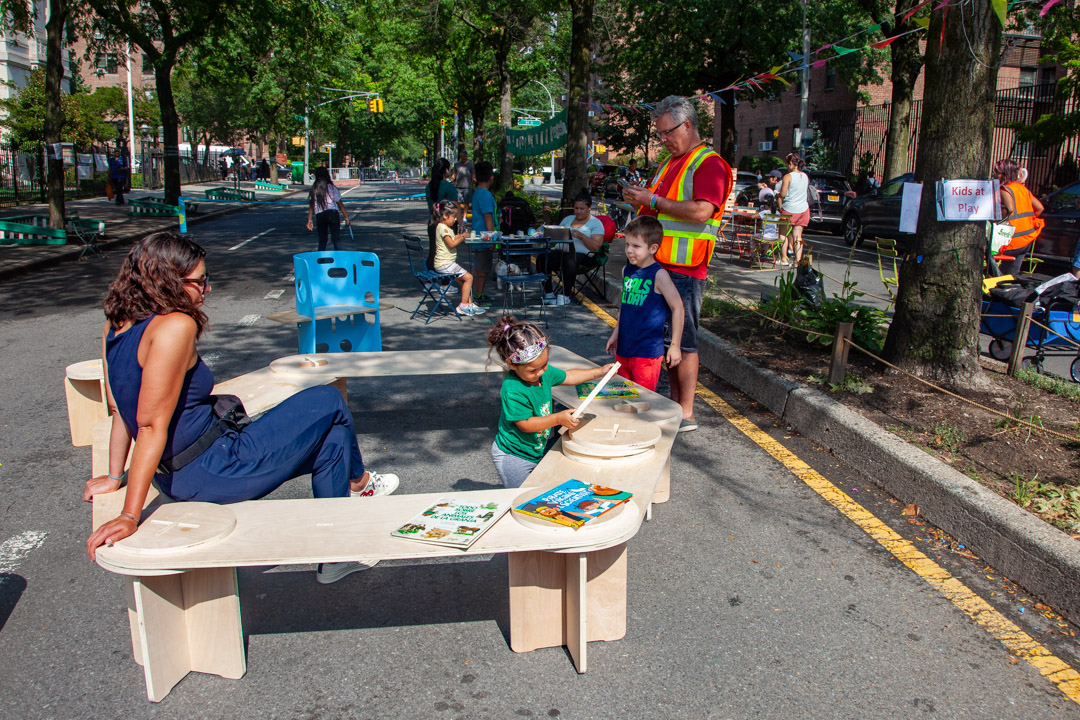 A set of benches on closed up street where children are playing.