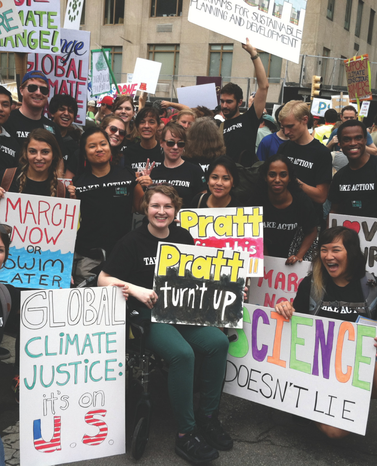 A group of students participating in a climate change march, holding various signs advocating for climate justice and action. The students are enthusiastic, with one holding a sign that reads