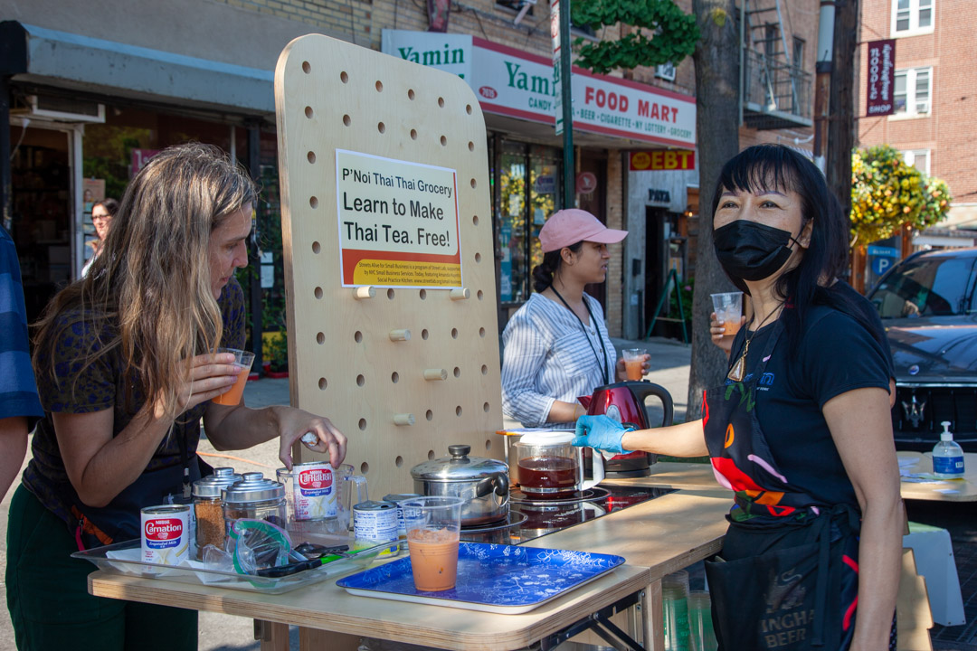A photo of a Thai iced tea stand on a busy street.