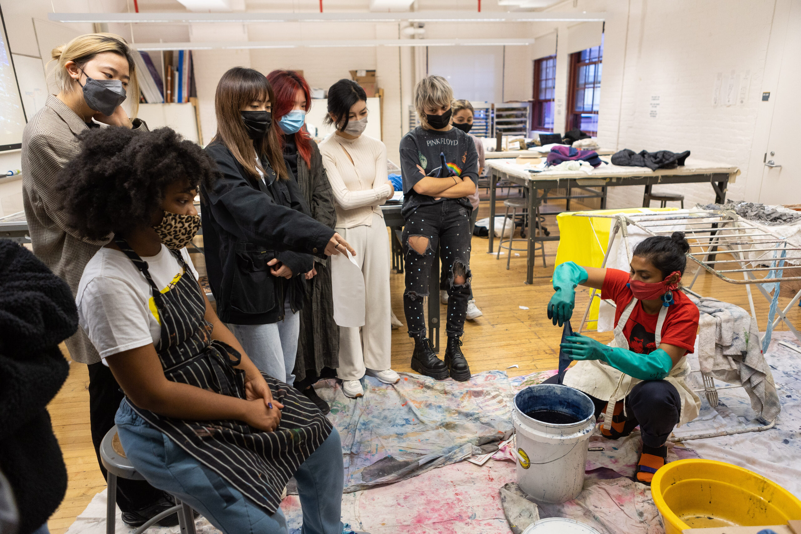 Students sitting in a studio watching a clothing dying process.