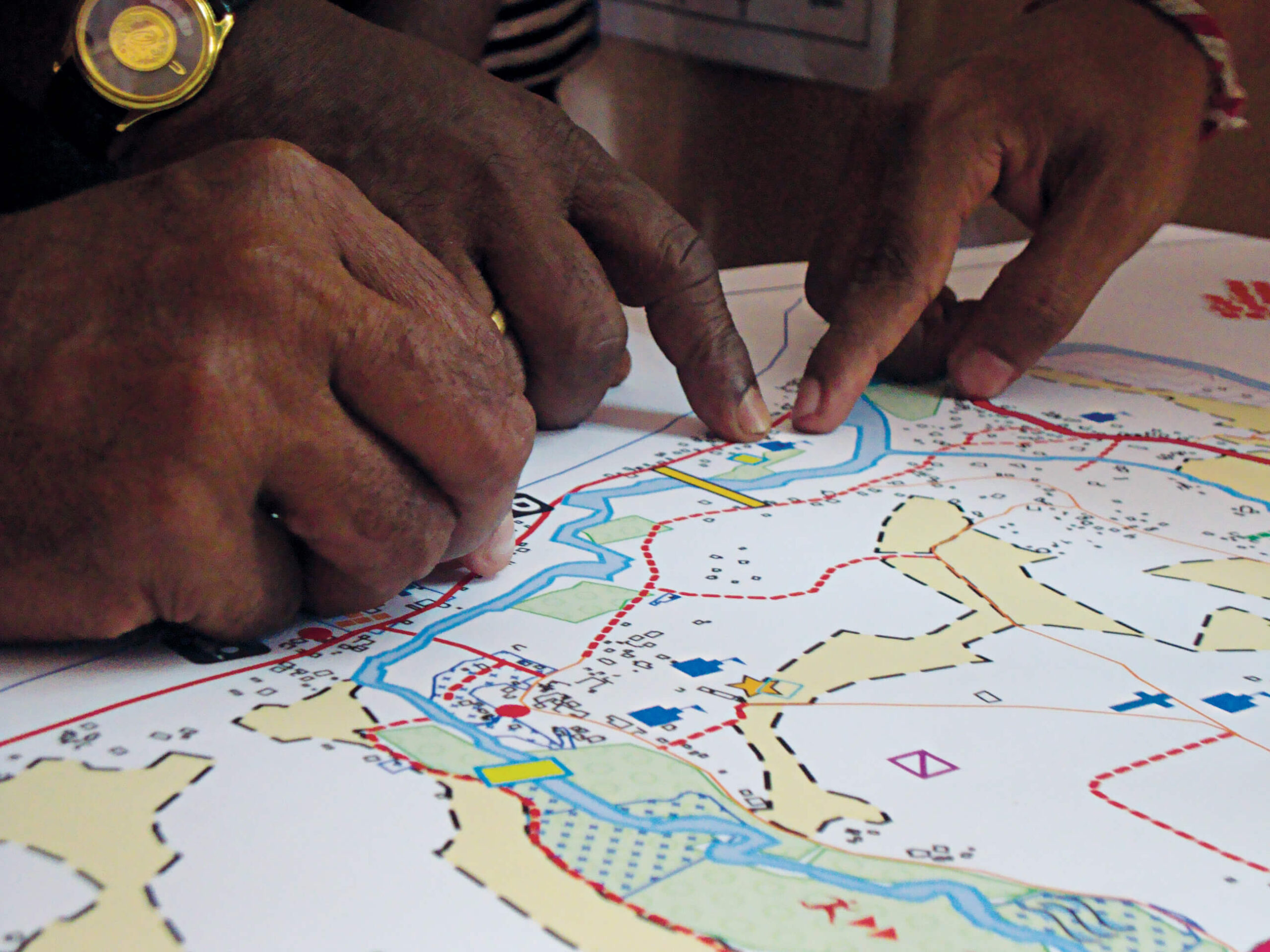A close up photo of two sets of hands point at things on a construction plan.