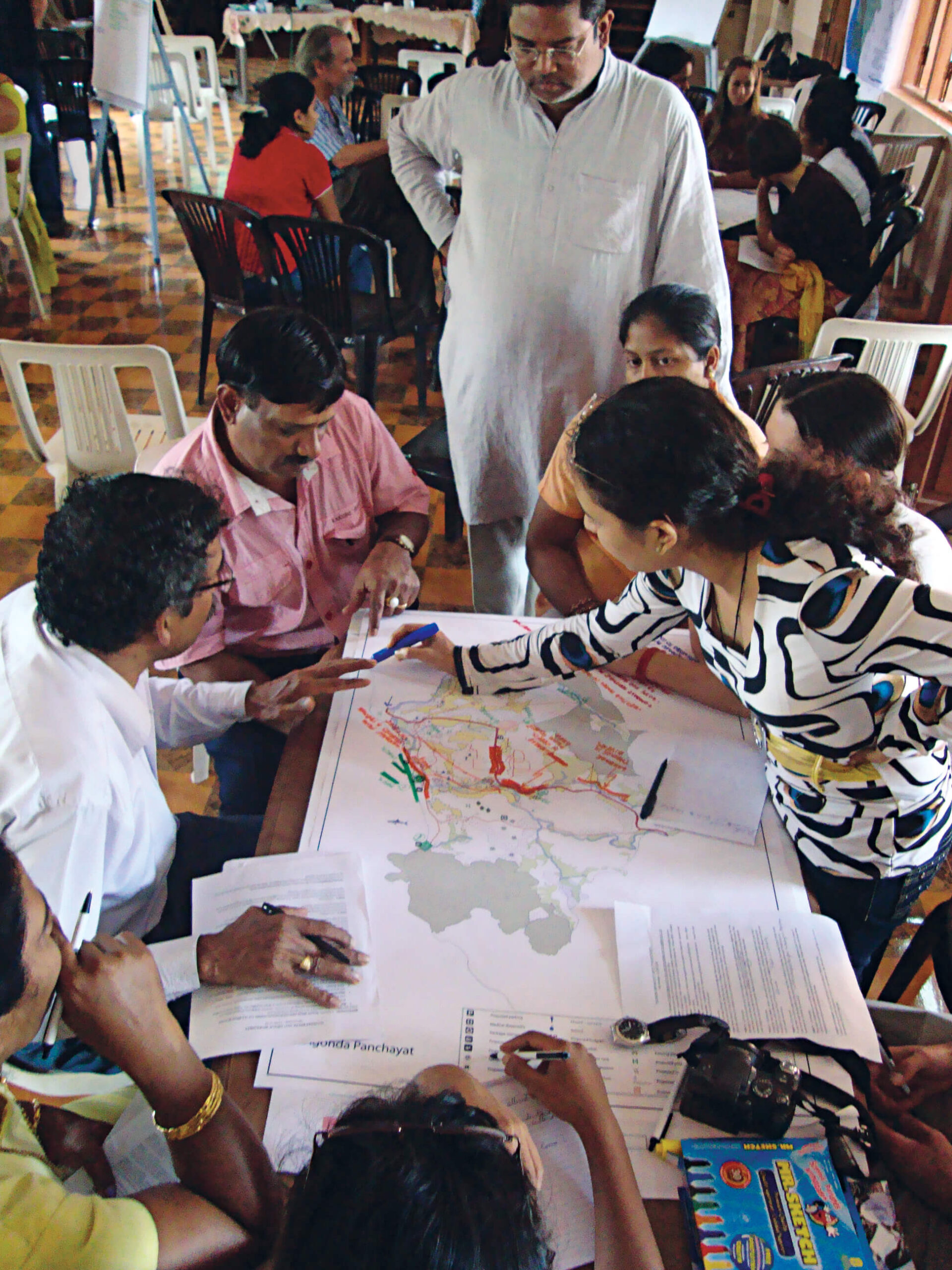 A group of people are gathered around construction plans as they discuss.