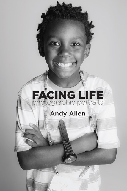 Black-and-white photo of child crossing arms and smiling wide, looking into the camera