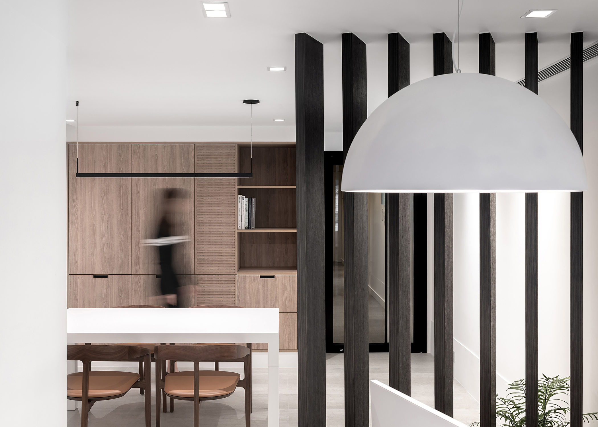 Small office area with wall of built-in wood storage cabinets, and a series of angled floor-to-ceiling wood beams dividing the room but allowing light through
