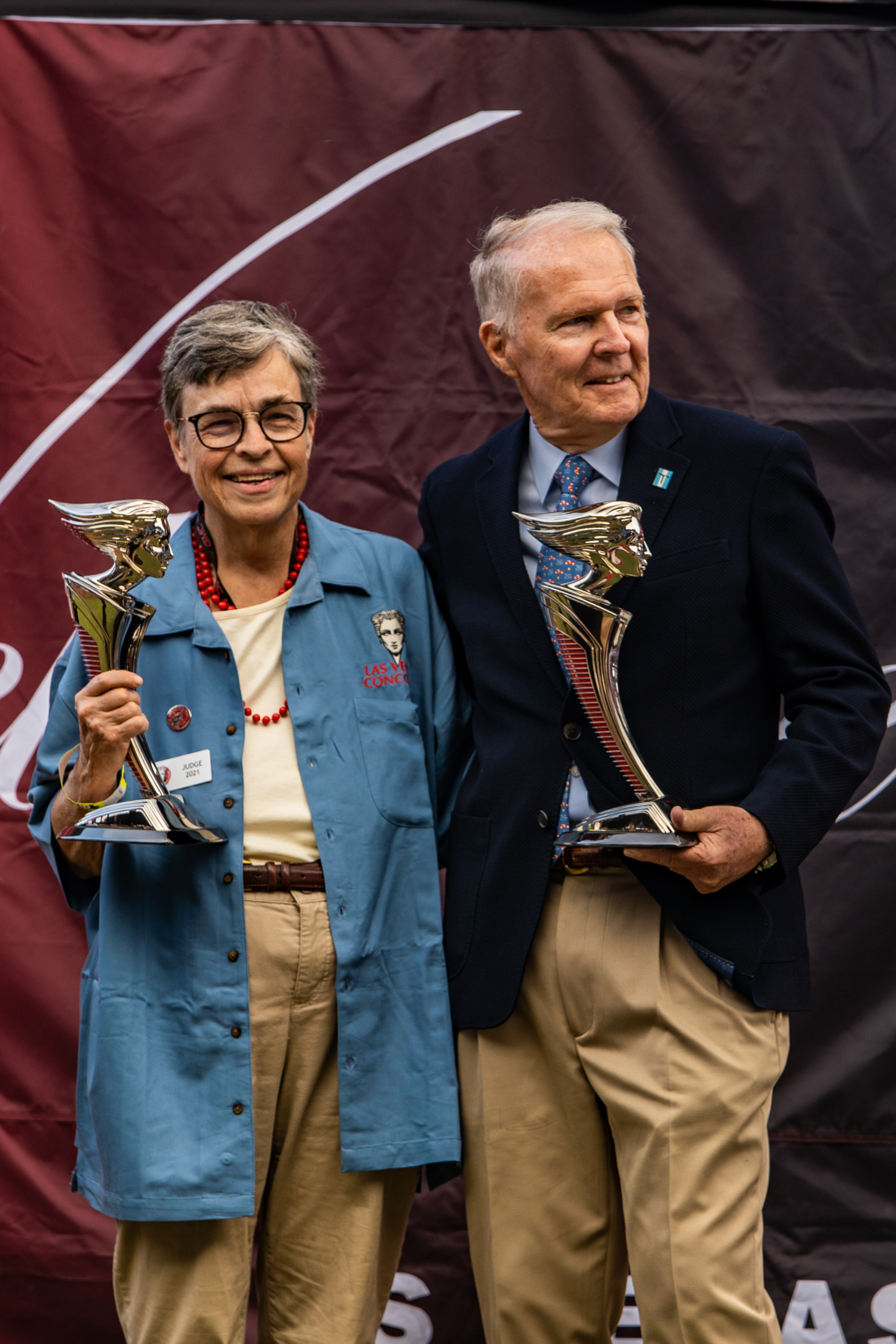 Two people pose smiling with golden award statuettes