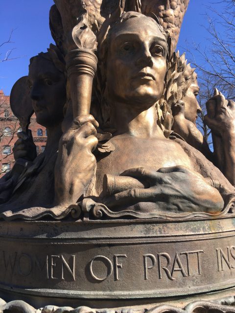 statue, with the words "women of pratt institute" emblazoned, with women holding torches