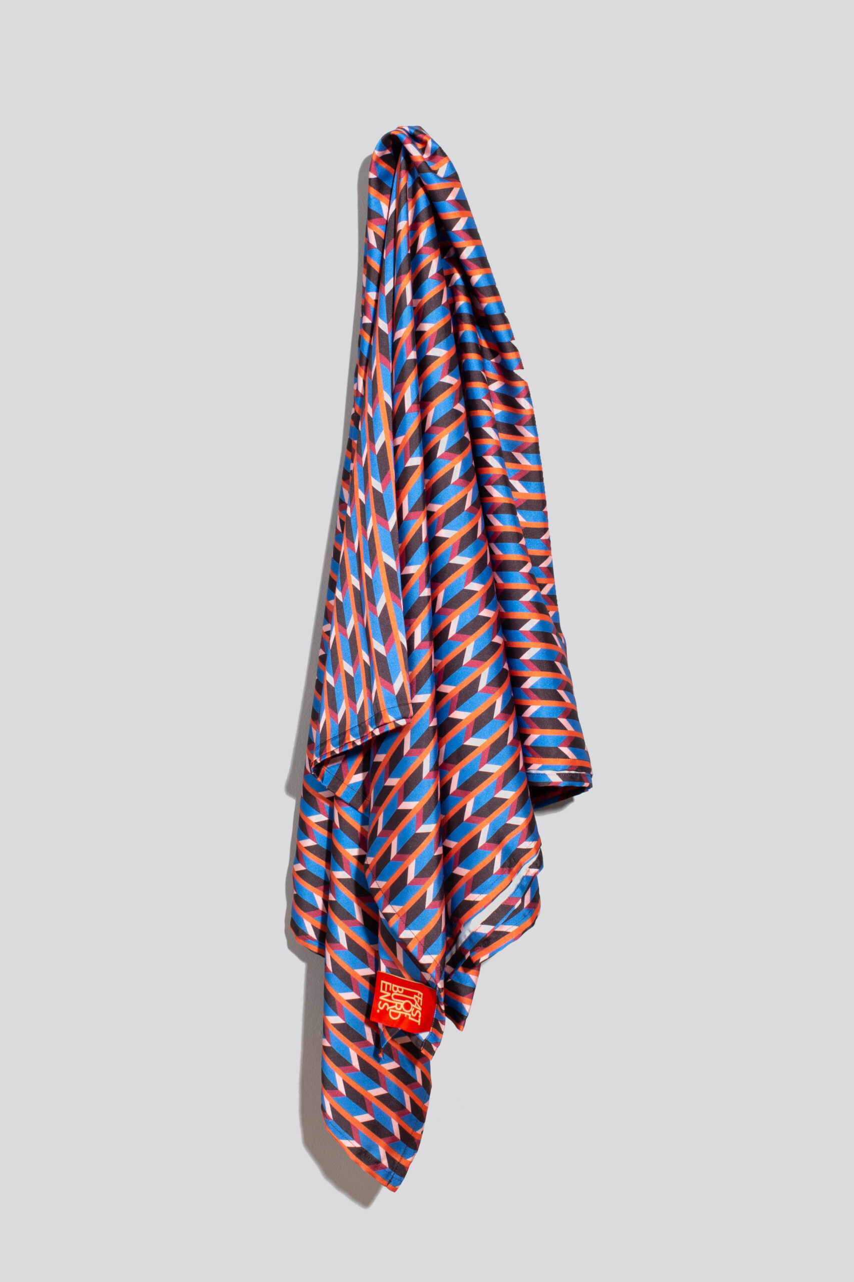 Silky tablecloth in blue, pink, red, and black chevron pattern draped on a wall