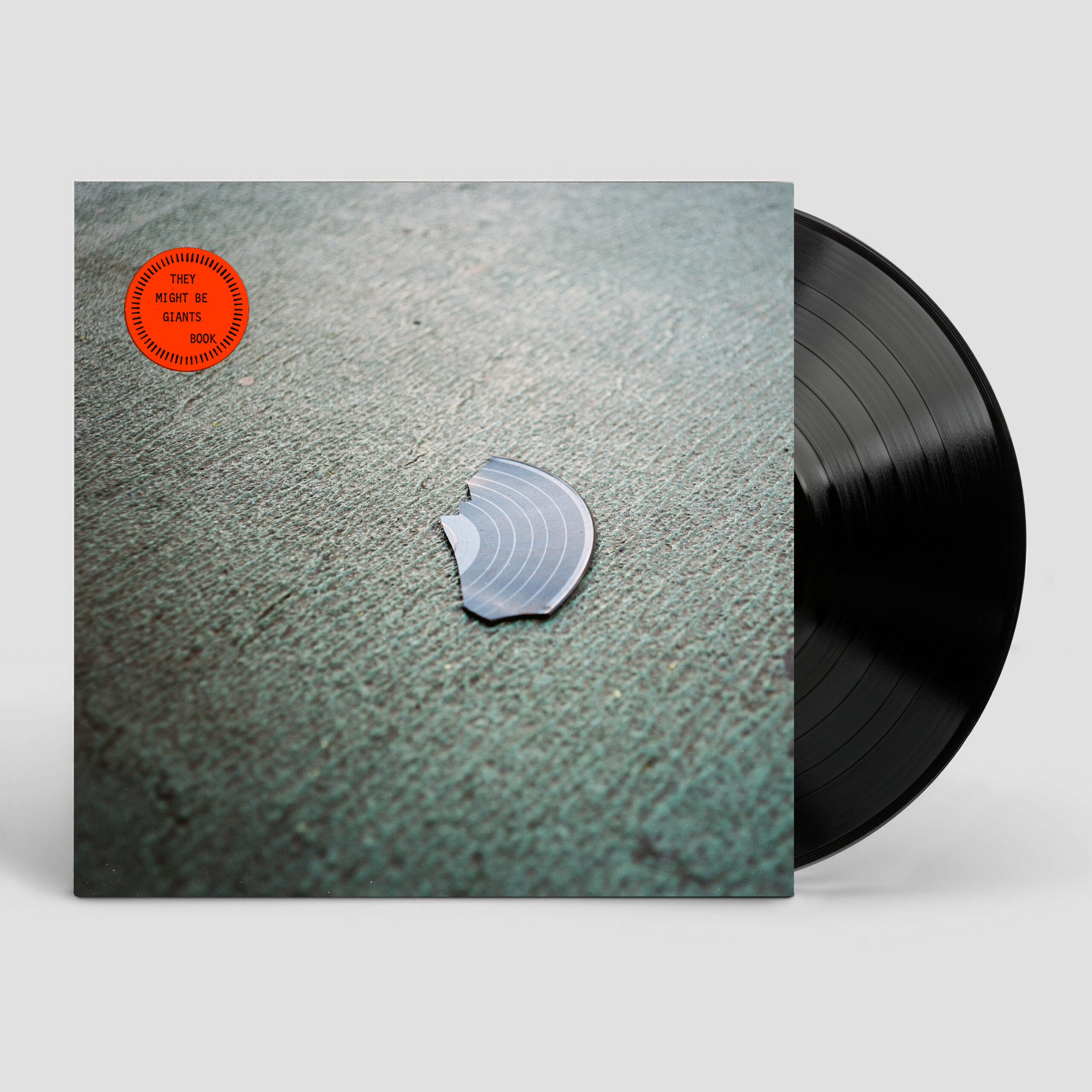 Vinyl record partially removed from slipcover with red title sticker and cover image of record fragment on a sidewalk